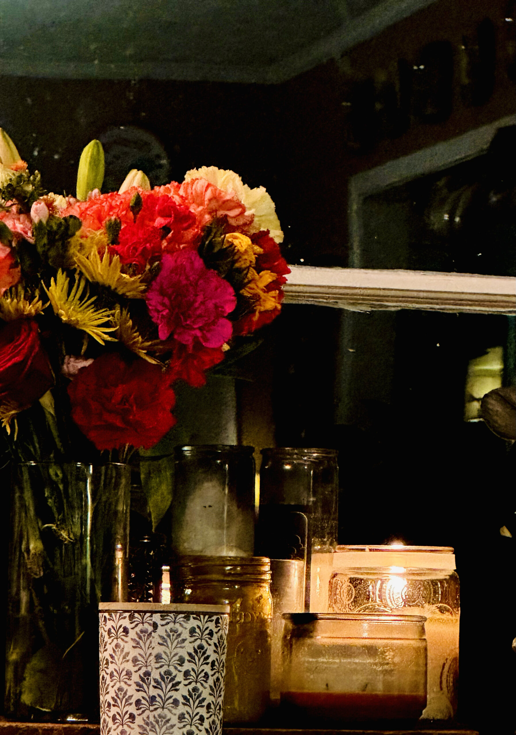 candle beside a vase of flowers